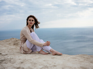 Fototapeta na wymiar pretty woman posing near rocks in the sand model Travel