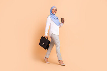 Full body photo of young arabic modern lady go with coffee bag wear headscarf shirt eyewear pants stilettos isolated on peach background