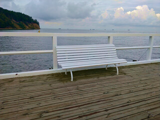 White bench on the wharf in the Sopot city in Poland during cloudy weather. The wharf has wooden...