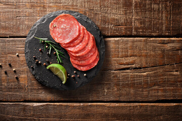 Salame fatiado sobre pedra escura sobre fundo de madeira envelhecida