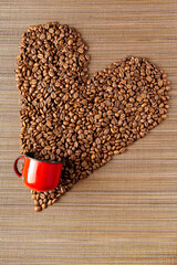 monte de grãos de café em formato de coração com caneca de ferro vermelha em fundo de madeira