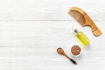 Fototapeta na wymiar Hair treatment oil with seeds and wooden hair comb. Top view