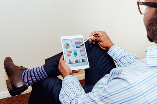 Back view of a business man examining financial statistics on tablet computer