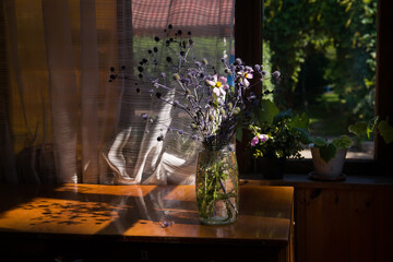 Wooden porch of the house with a bouquet of wild flowers. The veranda of a country house, a vase with flowers. Cozy veranda with summer decor. vintage interior, summer memory, the smell of wildflowers