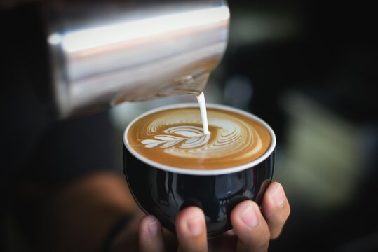 Barista pouring foam and milk to make cappuccino