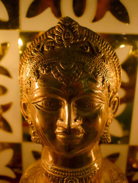 Close-up shot of golden Buddha statue in a candle lit room