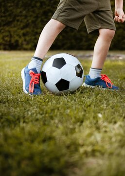Cropped image of boy playing soccer ball on green grass field