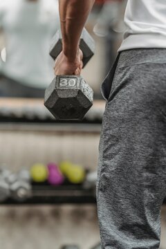 Cropped image of man holding gray dumbbell