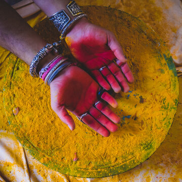 Cropped imaged of hands with purple gulal on them as part of Holy bath tradition