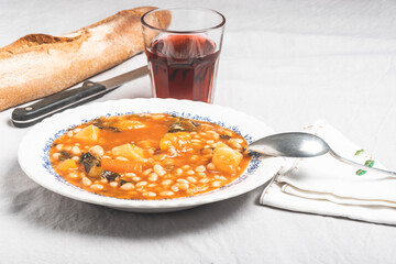 potage of white beans with a glass of red wine and bread in white background. Food Concept