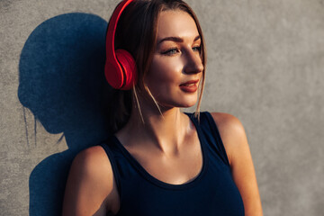 happy confident healthy sportswoman, listening to music with wireless headphones isolated on gray...