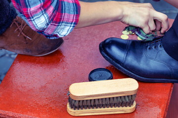 Shoe cream, brush close-up. Cleaning of boots on the street. wrong, care, footwear. Man's right...
