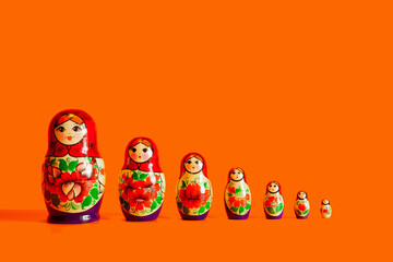  Family nesting dolls in a row stand on an orange background. Isolate.