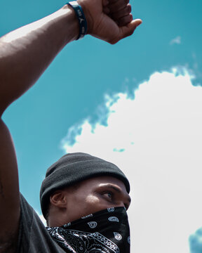 Man covering his face with bandana raising his arm at Black Lives Matter protests