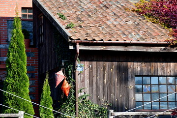A close up on two life buoys hanging from the roof of a wooden shack or hut with tiled roof next to...