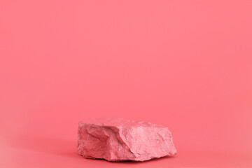 Pink stone, rock podium on the pink background. Podium for product, cosmetic presentation. Creative mock up. Pedestal or platform for beauty products.