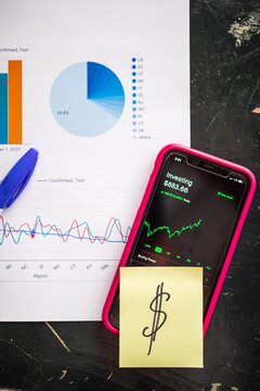 Smartphone with stock market app and pivot tables printed on paper