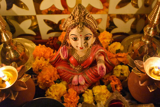 Small statue of Lakshmi Hindu Goddess surrounded by diya and flowers