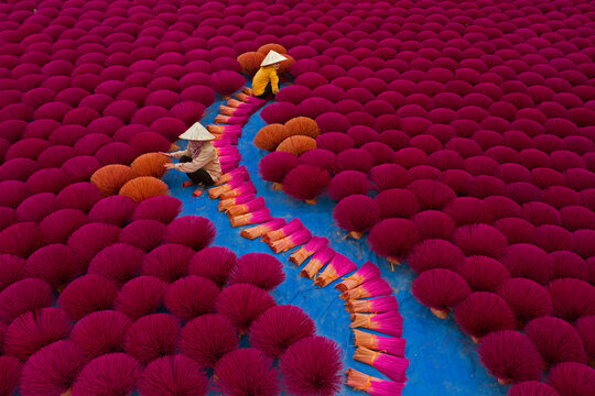 Vietnamese workers sit surrounded by thousands of incense sticks