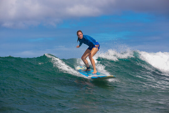 Woman in blue shirt surfing on sea waves