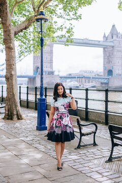 Woman in light floral dress standing near tower bridge