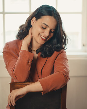Woman in orange shirt sitting on brown wooden chair
