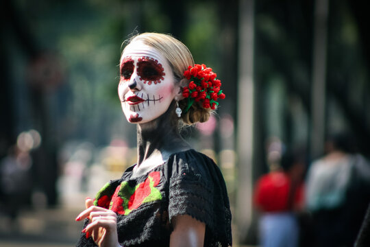 Woman with sugar skull face paint and Chiapas dress standing outdoor