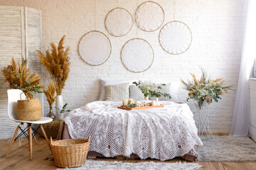 Beautiful home interior with white and beige tones, with dream catchers, dry flowers and a bed