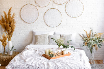 Beautiful home interior with white and beige tones, with dream catchers, dry flowers and a bed