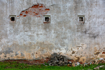 fragment of the whiteeashed briks wall of old building with the spot of  red briks oand three strange wholes