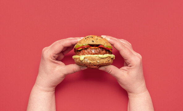 Vegan Burger Above View On A Red Table. Woman Holding A Veggie Burger.