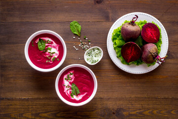 Red beet soup in white bowl with raw beet roots