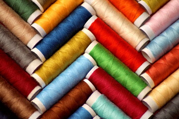 spools of multicolored sewing thread lie in a herringbone pattern