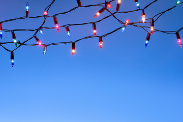 Christmas lights string on blue background with copy space..