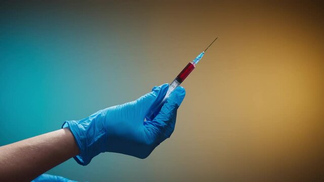 Doctor opening syringe with red solution. Nurse wearing protective white gloves showing sample of medicine, vaccination against covid-19, laboratory research concept. Coronavirus vaccine.