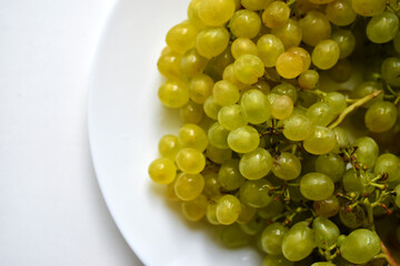Homemade green ripe grapes on a white plate