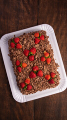 Chocolate cake, a beautiful chocolate cake with strawberries on a white shape on rustic wood, abstract background, Top view.