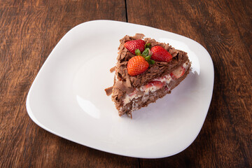 Chocolate cake, a tasty slice of chocolate cake with strawberries on a white plate on rustic wood, abstract background, selective focus.