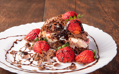 Chocolate cake, a tasty slice of chocolate cake with strawberries on a white plate on rustic wood, abstract background, selective focus.