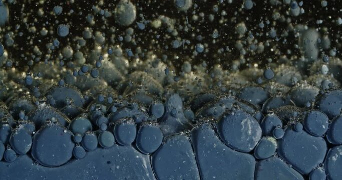 Blue paint bubbles bouncing in water