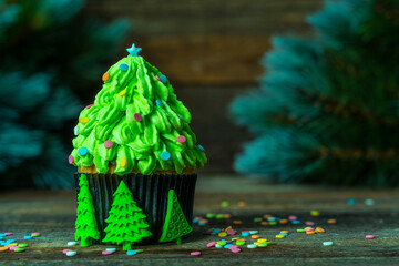 Christmas tree made of cupcake, cream decorated with confetti. New Year card. Christmas in a rustic style. copy space. Christmas background with fir tree and confetti. Background blurry out of focus.