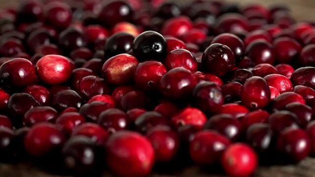 Hand is adding more cranberries to table with many cranberries