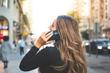 Young caucasian woman using a smartphone at Madrid's Gran Via avenue, Spain.