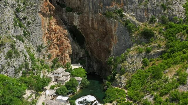 Aerial: Scenic View Of Structures At Vrelo Bune, Drone Descending Over Buna River Amidst Forest Over Mountains - Blagaj, Bosnia and Herzegovina