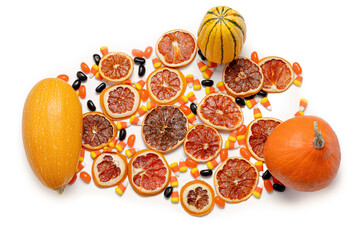 Dried orange slices, candies, squash, and pumpkin isolated on a white background from above.