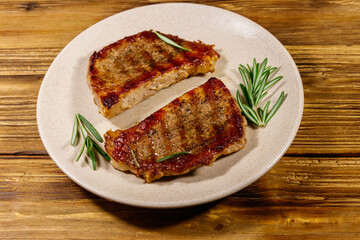 Grilled pork steaks with rosemary on wooden table