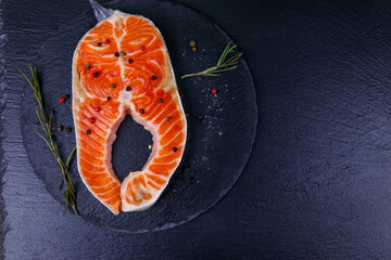 Raw salmon steak with spices on black slate. Top view