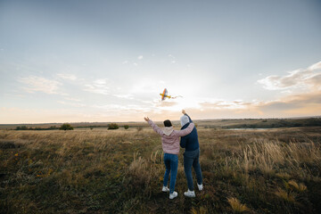 A happy couple flies a kite and spends time together in the fresh air. Happy relationship and family vacation.