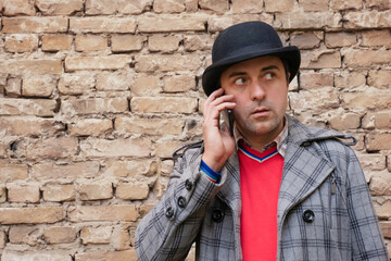 Middle-aged man outdoors talking on the phone against a brick wall background