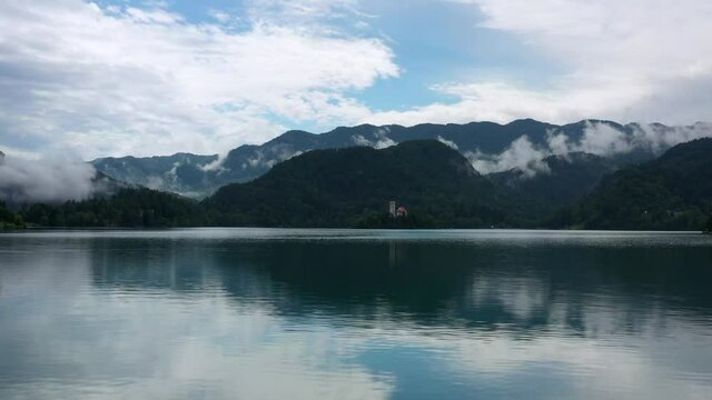 Aerial: Beautiful Shot Of Forest Over Mountains Against Cloudy Sky, Drone Flying Ascending Over Lake Bled